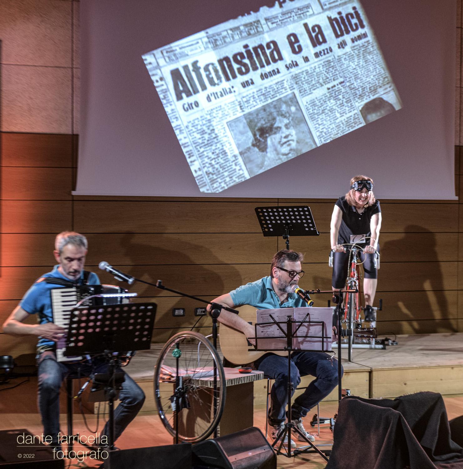 Maria Giulia Campioli in bicicletta, accompagnata da Stefano Garuti alla fisarmonica e Francesco Grillenzoni alla chitarra.